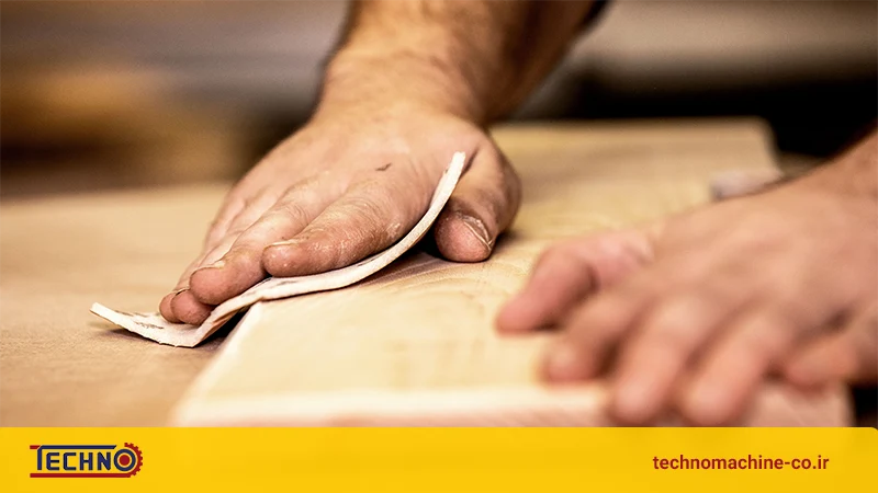 شخصی در حال سنباده زدن چوب با دست بدون دستکش